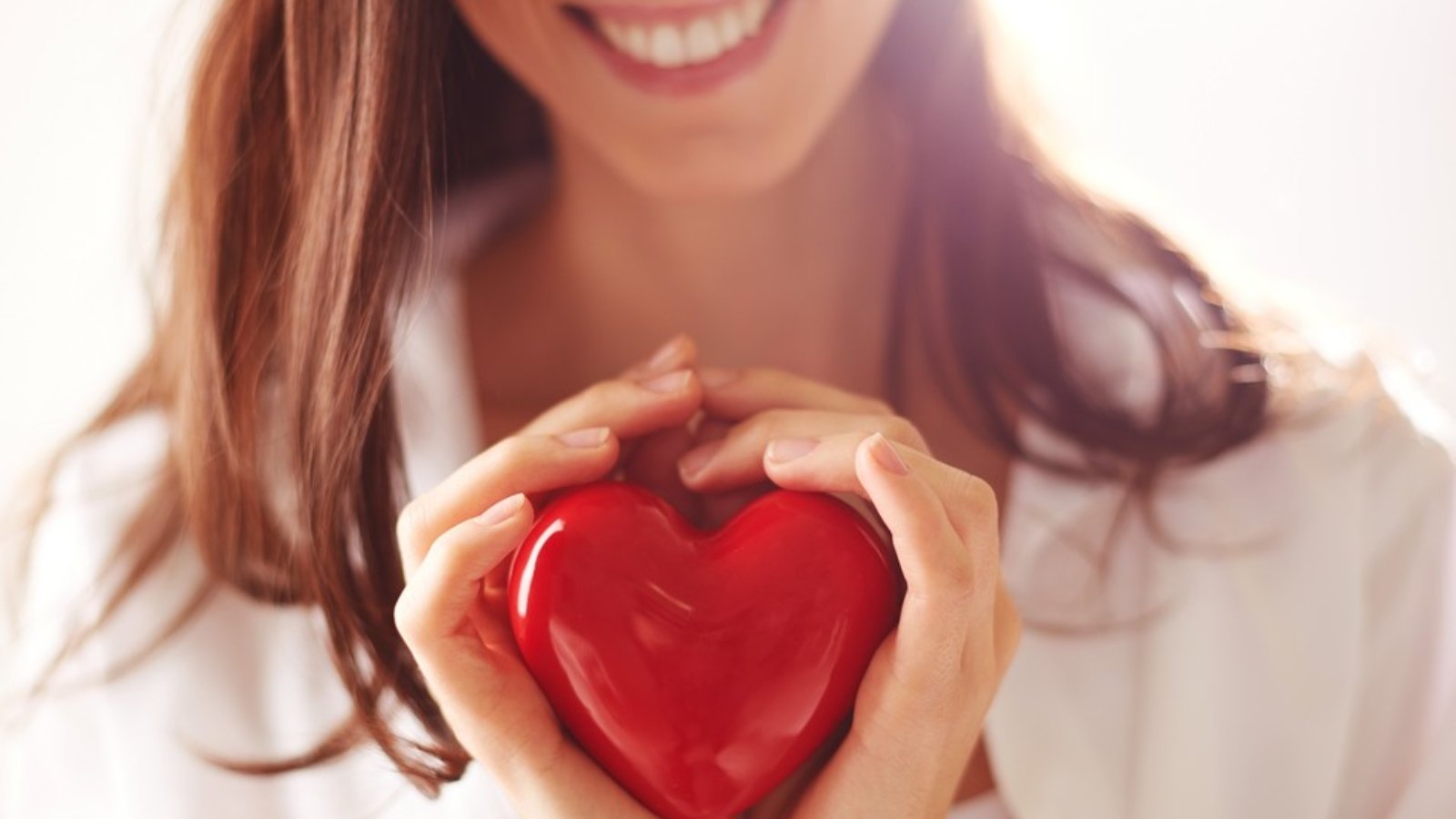 Close-up of smiling female holding red heart