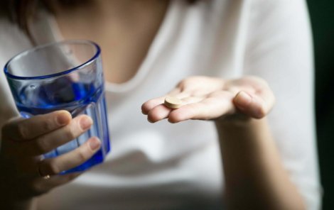 Female hands holding pill and glass of water, woman taking supplements or antibiotic antidepressant painkiller medication to relieve pain headache, contraception side effects concept, close up view