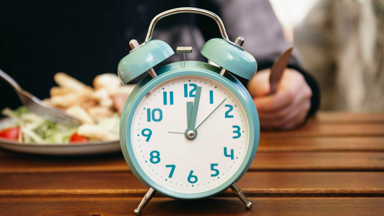 Alarm clock of blue which schedule of meal for weight loss and Intermittent fasting concept.
