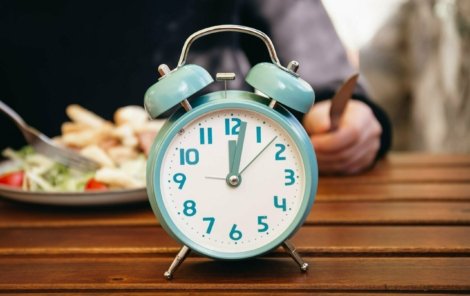 Close-up, alarm clock on a blurred food background.