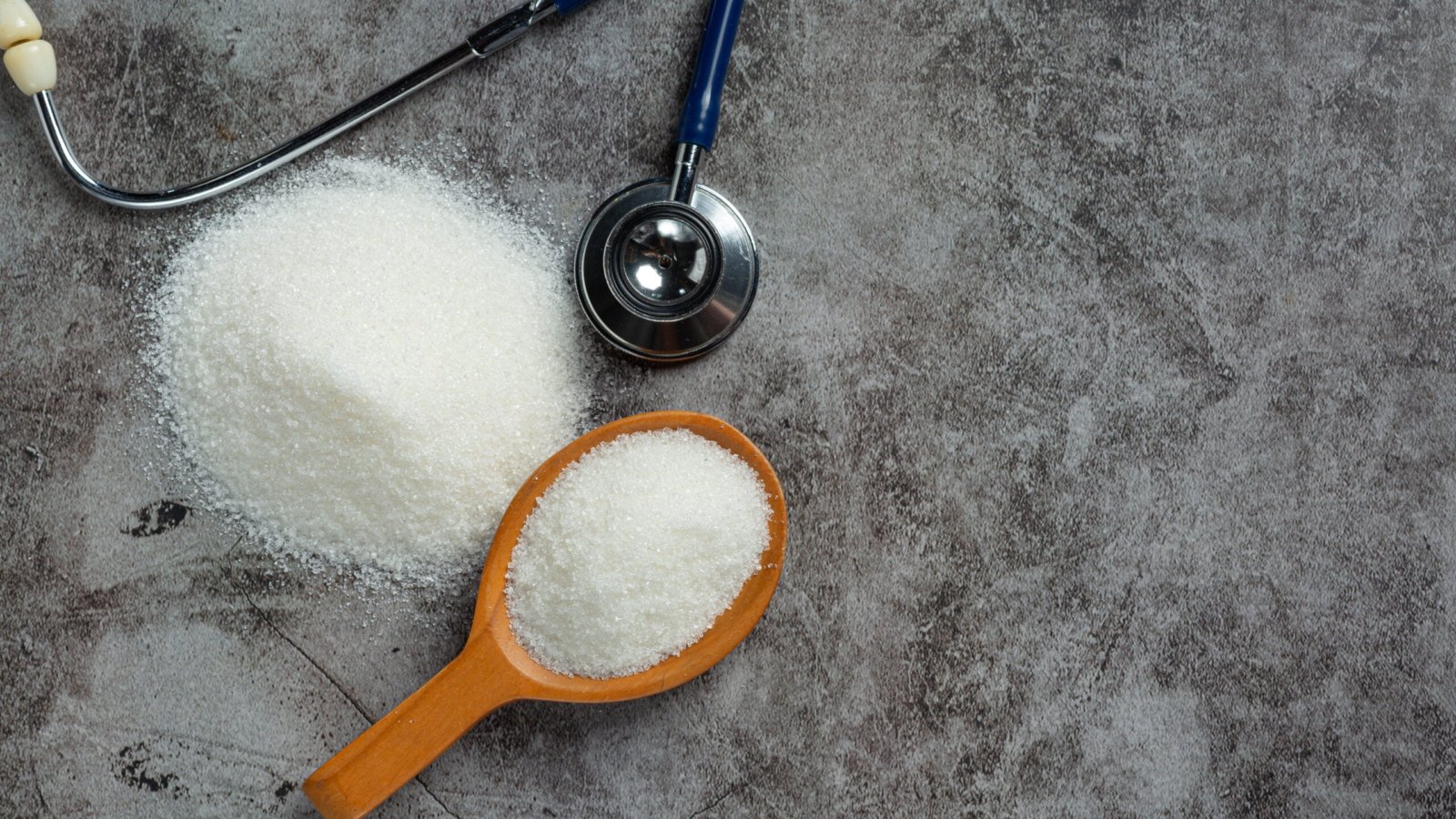 World diabetes day; sugar in wooden bowl and stethoscope on dark background