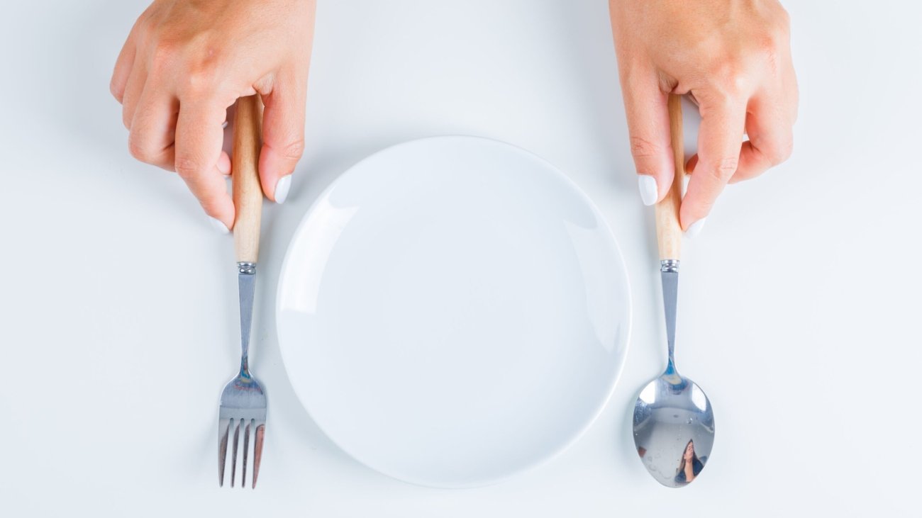 Meal concept with empty plate on white background flat lay. hands holding fork and spoon.