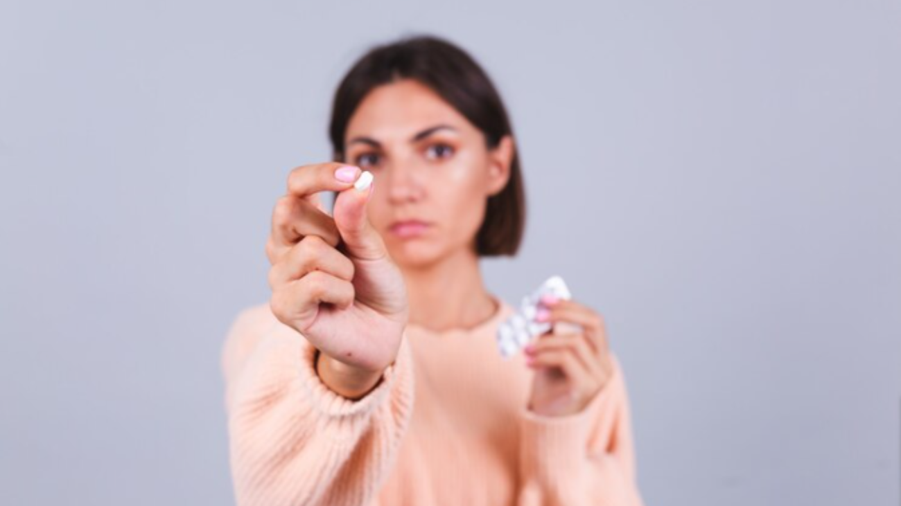 Free-Photo-Free-photo-woman-in-sweater-on-gray-wall-holds-mug-and-pills-with-unhappy-sad-expression-on-face