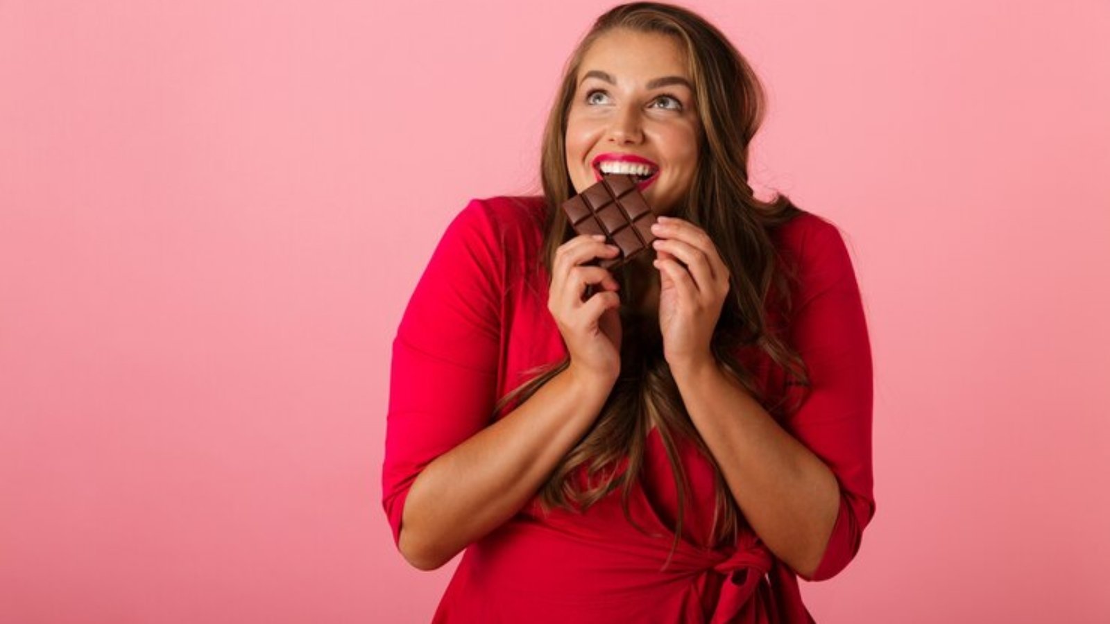 image-pretty-hungry-young-woman-isolated-pink-wall-holding-chocolate_171337-51469