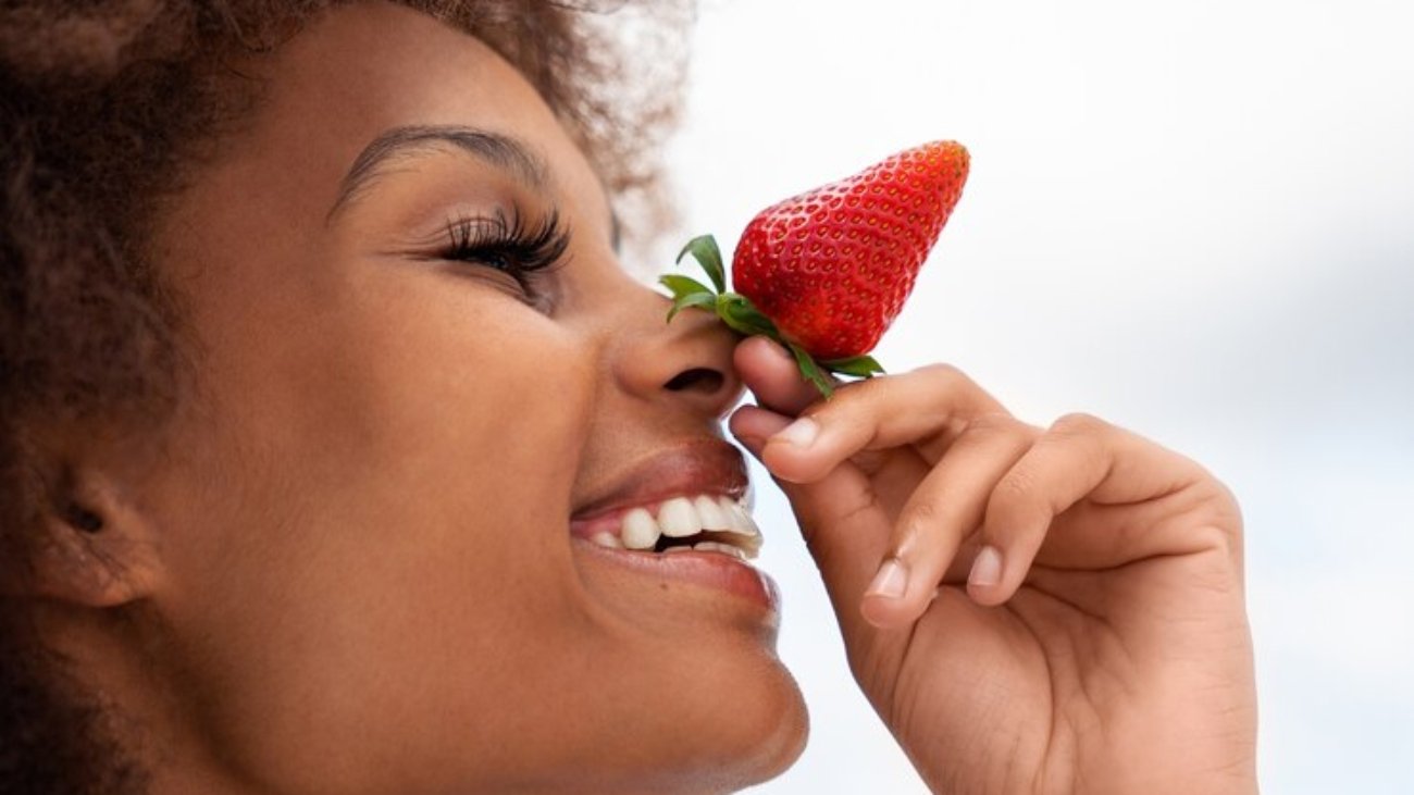 side-view-smiley-woman-holding-strawberry_23-2150100270