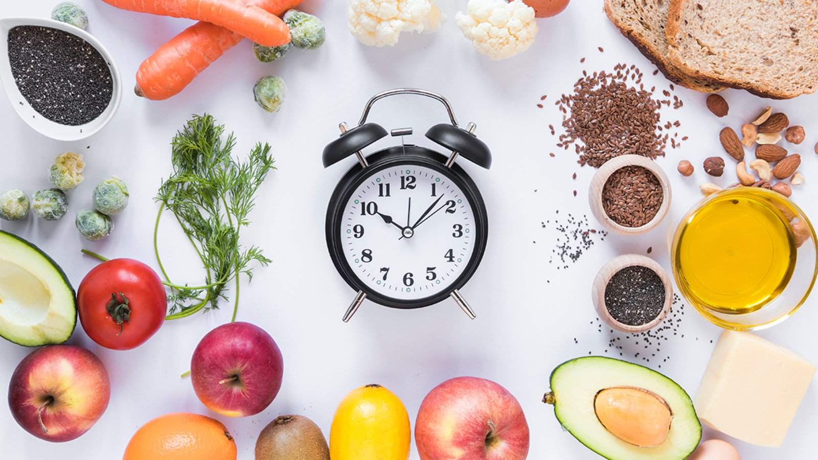 variety-ingredients-with-alarm-clock-arranged-against-isolated-white-background