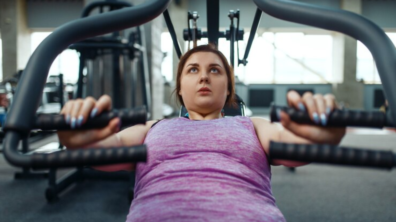overweight-woman-exercise-machine-gym-top-view-active-training