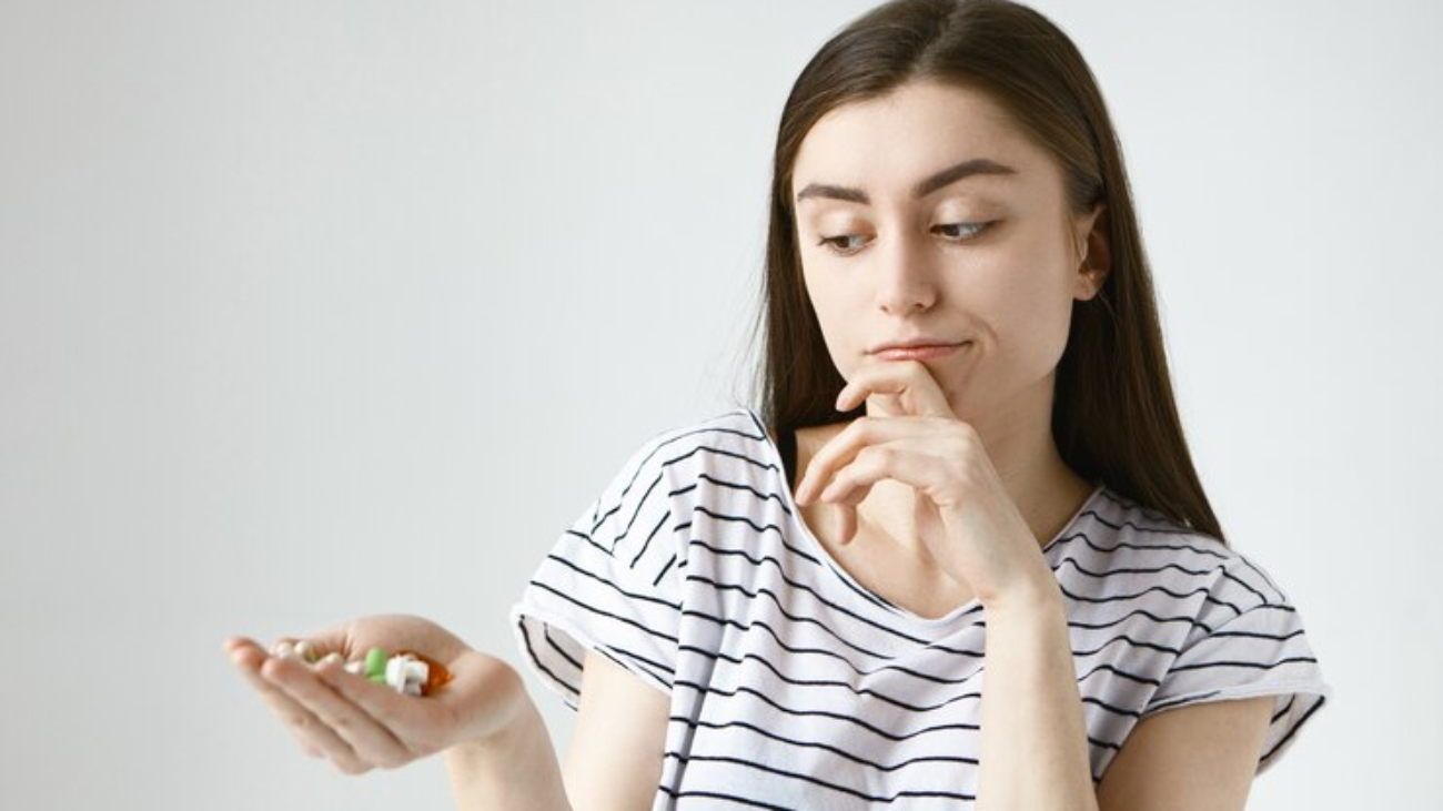 isolated-indecisive-doubtful-young-lady-with-loose-dark-hair-rubbing-chin-thoughtfully-looking-colorful-pills-her-palm-going-take-them_343059-1391-jpg-740×493-